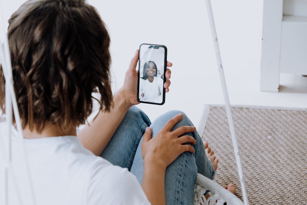A young woman engages in a cheerful video call with a friend using a smartphone.
